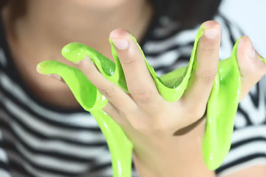 یک اسلایم سبز رنگ در دستان یک کودک